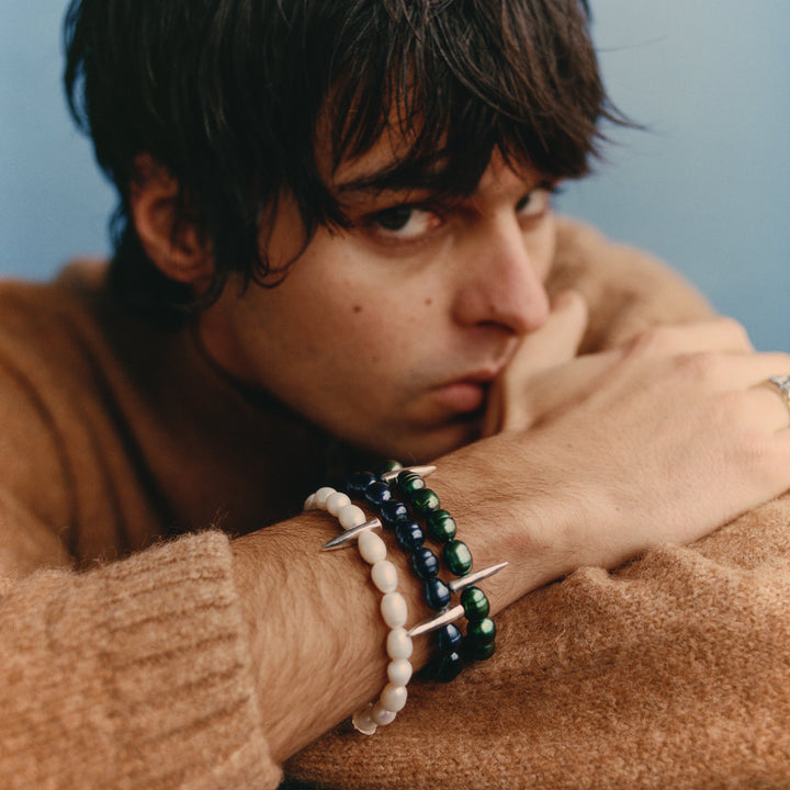 Person wearing bracelets with a neutral background