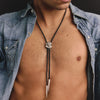 Man wearing a denim shirt with a bolo tie, shirt open to reveal chest.