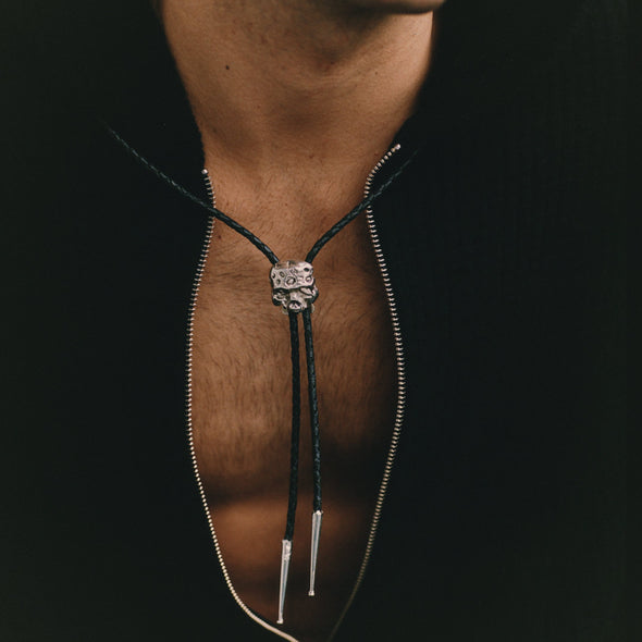 Close-up of a person wearing a black bolo tie with a silver clasp.