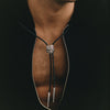 Close-up of a person wearing a black bolo tie with a silver clasp.