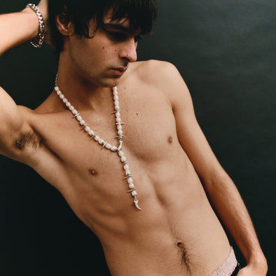 Man with a necklace against a dark background