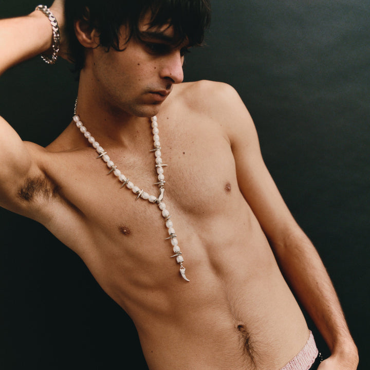 Man with a necklace against a dark background