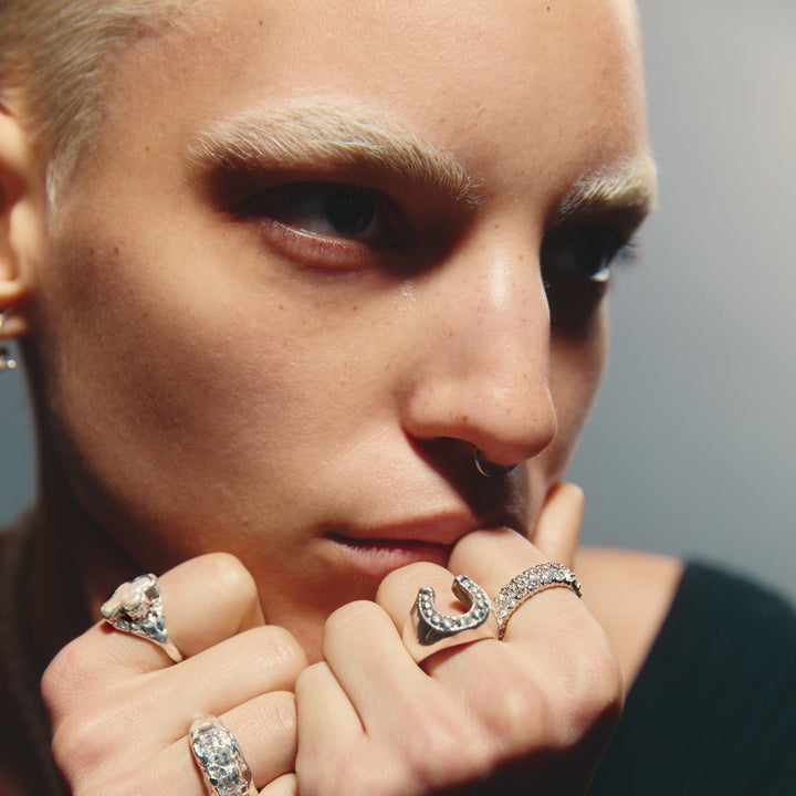 Close-up of a person wearing multiple rings with a neutral background