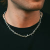 Silver chain necklace worn by a person on a black background