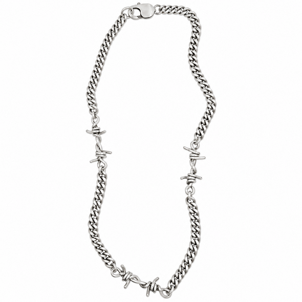 A silver-toned curb chain necklace featuring integrated barbed wire motifs at intervals, displayed on a clean white background.