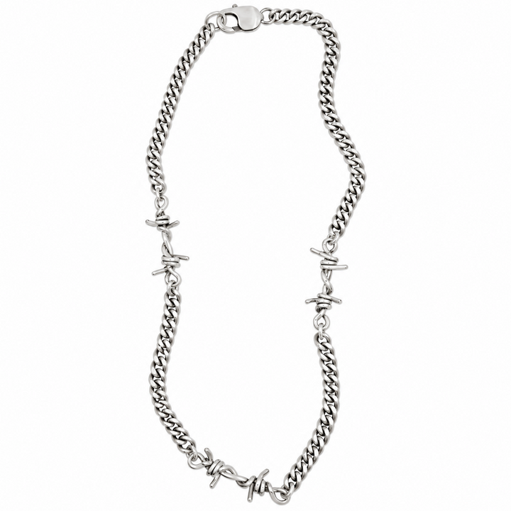 A silver-toned curb chain necklace featuring integrated barbed wire motifs at intervals, displayed on a clean white background.