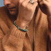 Person wearing a brown sweater with jewelry against a blue background