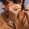 Person wearing a brown sweater with jewelry, including a ring and bracelet.