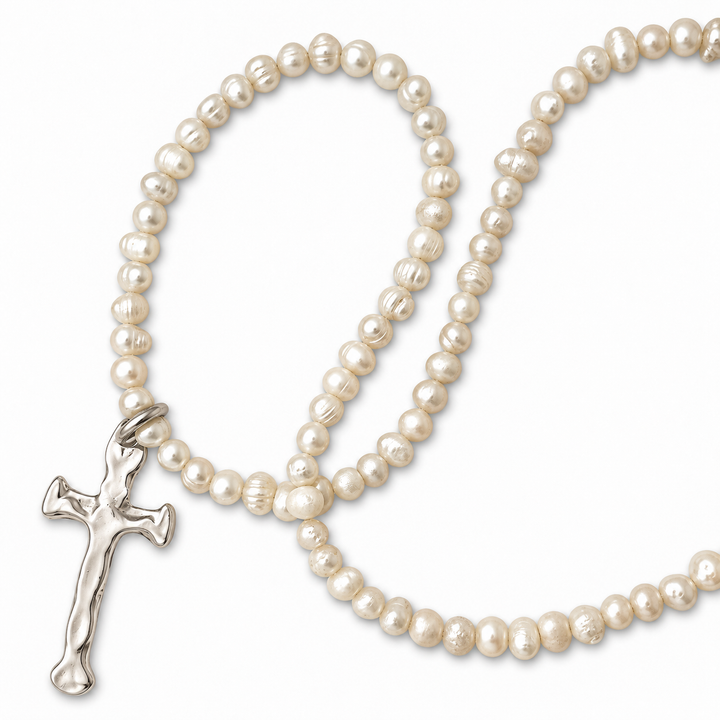 A strand of irregular white freshwater pearls with a textured silver crucifix pendant, arranged on a clean white background.