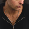 Man wearing a black sweater and silver necklace against a dark background