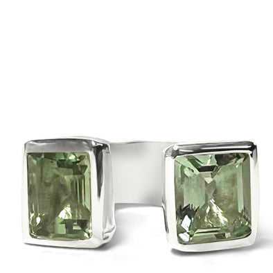 Silver ring with two green gemstones on a white background