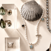 Jewelry including a bracelet, necklace, and rings displayed on a neutral background with shells.