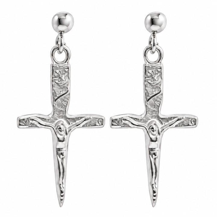 A pair of silver crucifix dangle earrings with textured hilts, detailed corpus figures, and round ball studs on a plain white background.
