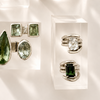 Jewelry display with green gemstone rings and earrings on a white background