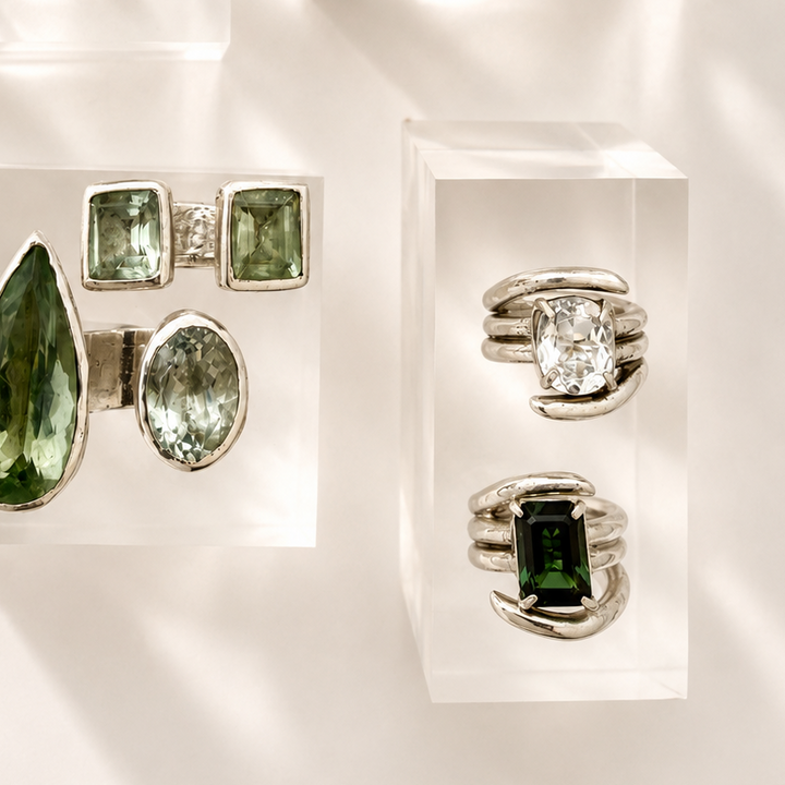 Jewelry display with green gemstone rings and earrings on a white background