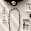 Jewelry including a necklace, earrings, and rings displayed on a white surface.