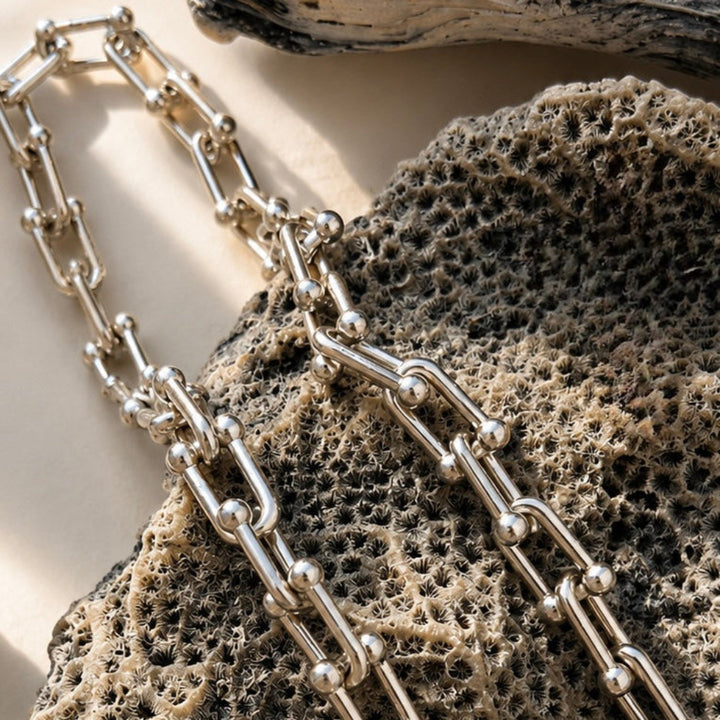 Silver chain necklace on a textured stone surface