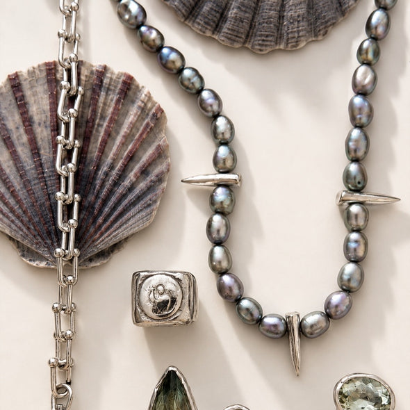 Jewelry set with pearls, silver chain, and shell elements on a light background