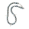 Necklace with greyish green pearls and silver spike-like elements on a white background