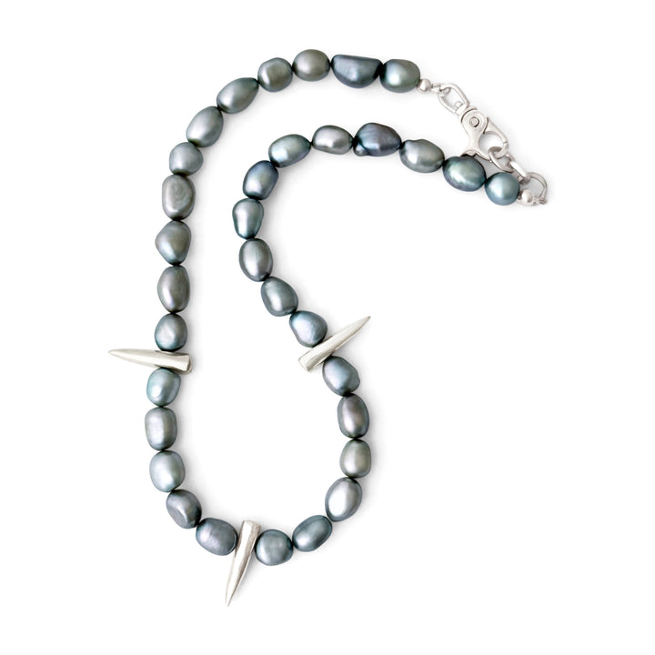 Necklace with greyish green pearls and silver spike-like elements on a white background