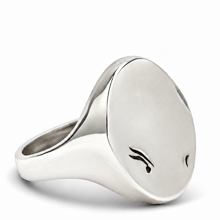 A polished silver signet ring with a flat oval face featuring two small black engraved or printed symbols, shown on a clean white background.