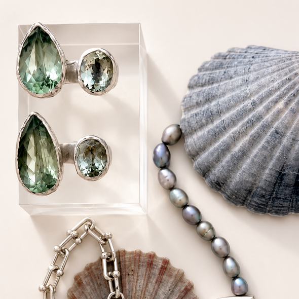 Jewelry including earrings, a bracelet, and a necklace with seashells on a light background