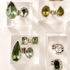 Jewelry display with green gemstone rings and earrings on a white background