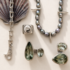 Jewelry set with pearls, silver chain, and green gemstones on a light background