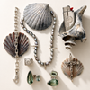 Collection of silver jewelry and shells on a light background