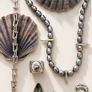 Jewelry set with pearls, silver chain, and shell elements on a light background
