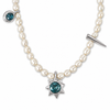 A pearl necklace with a silver-toned starburst pendant featuring a round teal-blue gemstone, a small matching teal-blue stone in a bezel setting on one side, and a pointed spike charm on the other side, shown against a plain white background.