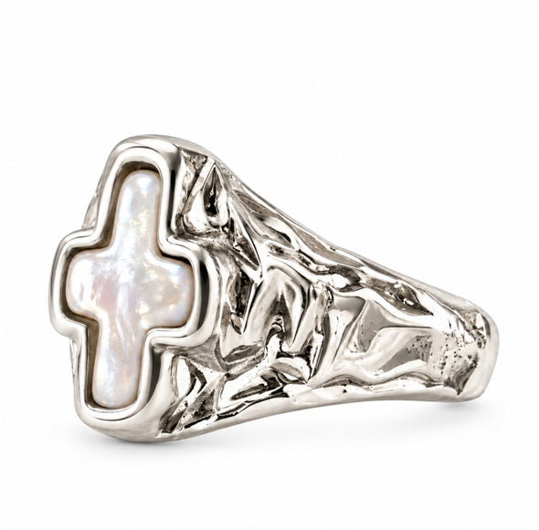 A silver signet-style ring featuring a textured, organic-shaped silver band and a central cross-shaped inlay of iridescent mother-of-pearl, shown on a plain white background.