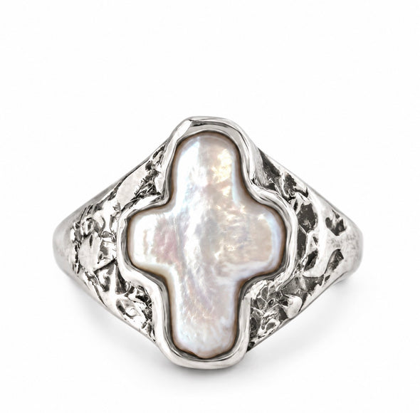 A silver signet ring featuring a large, irregularly shaped white mother-of-pearl cross-shaped centerpiece, set against a clean white background.