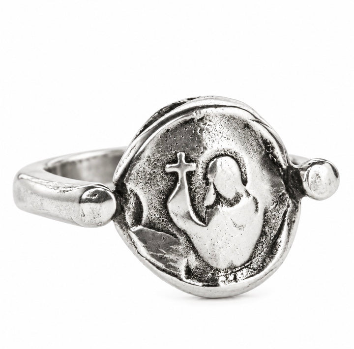 A silver-toned metal ring featuring a circular medallion with an embossed figure holding a cross, photographed on a clean white background.