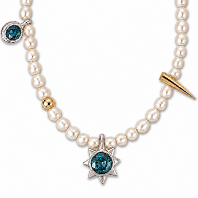 A pearl necklace featuring a central silver starburst pendant with a deep blue gemstone, a gold accent bead, a gold spike charm, and a smaller blue gemstone pendant on the side, set against a plain white background.