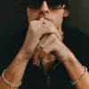 Person wearing rings and a bracelet with a dark background