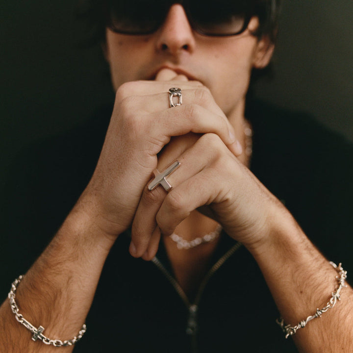 Person wearing rings and a bracelet with a dark background