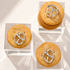 Silver pretzel-shaped earrings on top of round cookies with a clear acrylic stand.