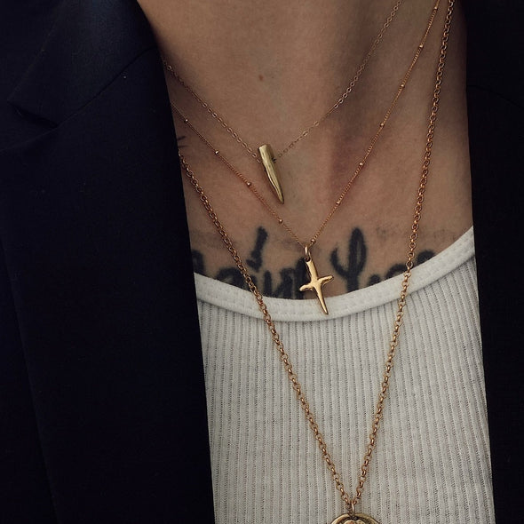 close up shot of models neck with our mini cross dagger necklace