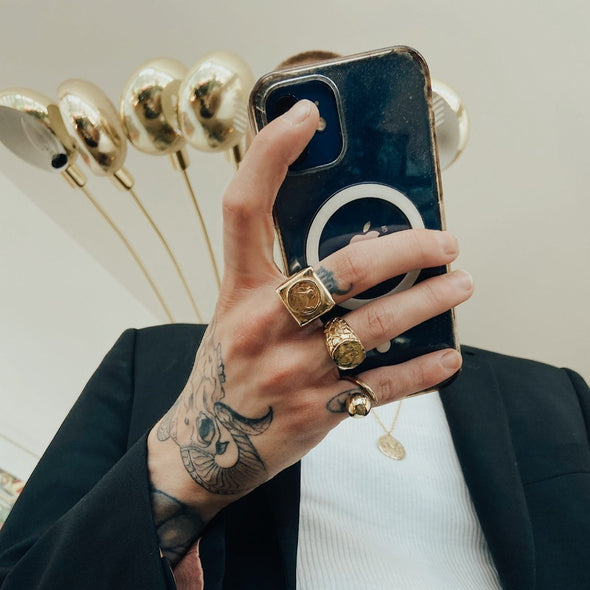 male model holding a phone in his hand wearing our saint signet