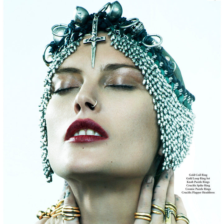 custom made headpiece made out of silver and various metals, featuring a large crucifix dagger in the center of the forehead and different shapes of hoops and beads hanging from it.