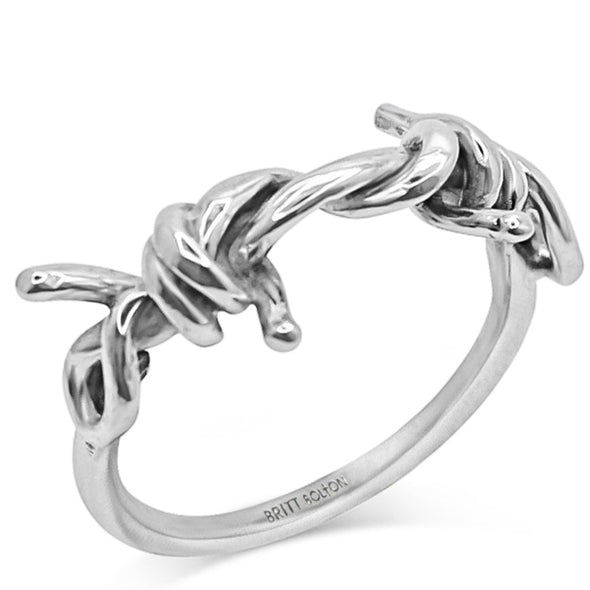 Silver ring with barbed wire shape standing over white background