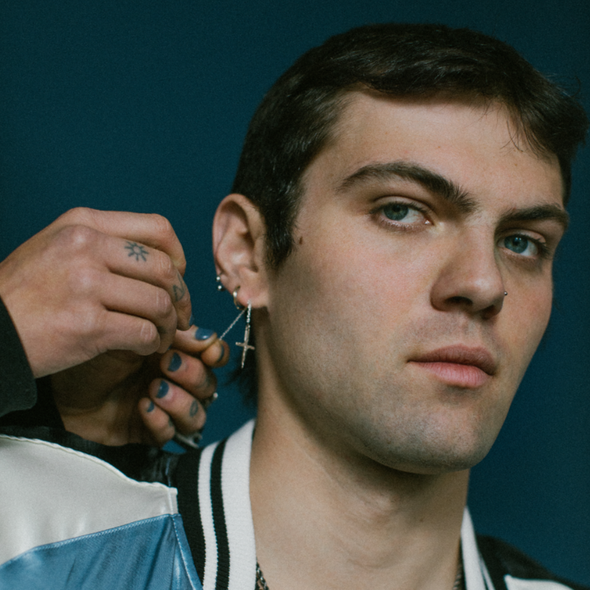 male model wearing our crucifix dagger threader earring with blue background