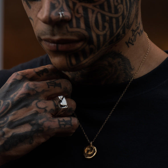 male model with tattoes on his face and hand, wearing our mirror chunk ring