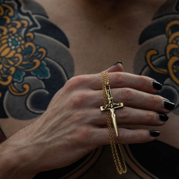close up shot of hands holding our xl crucifix dagger necklace