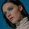 female model in blue background wearing our xl cross hoop earrings