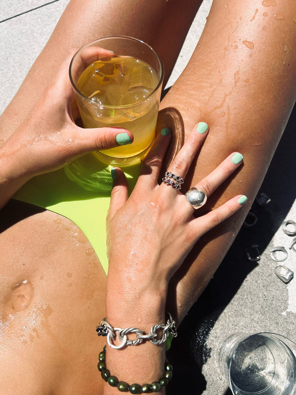 model posing in summer setting holding a drink in her hand, wearing our Handmade Sterling Silver bubble ring with a shiny finish 